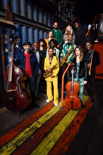 A group of musicians pose with instruments inside an industrial-style venue