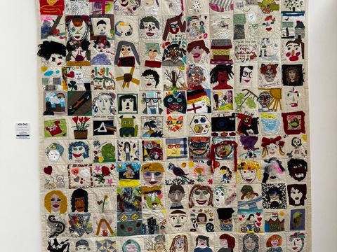 Picture of a tapestry with multiple images of faces, hand-sewn self-portraits