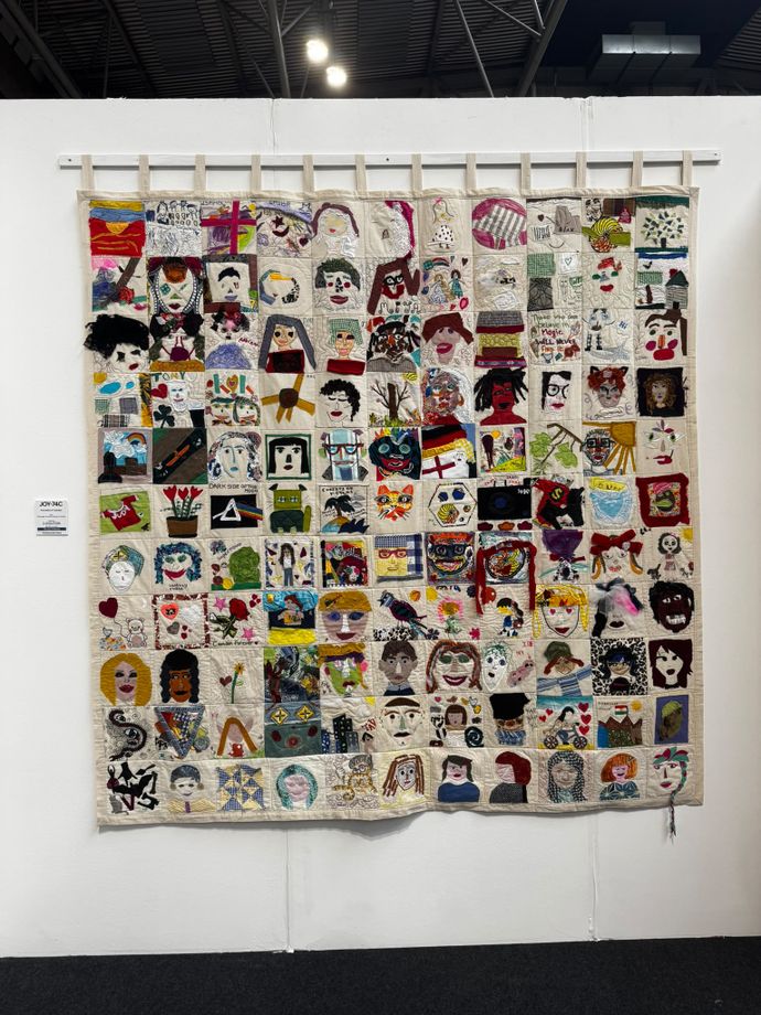 Picture of a tapestry with multiple images of faces, hand-sewn self-portraits