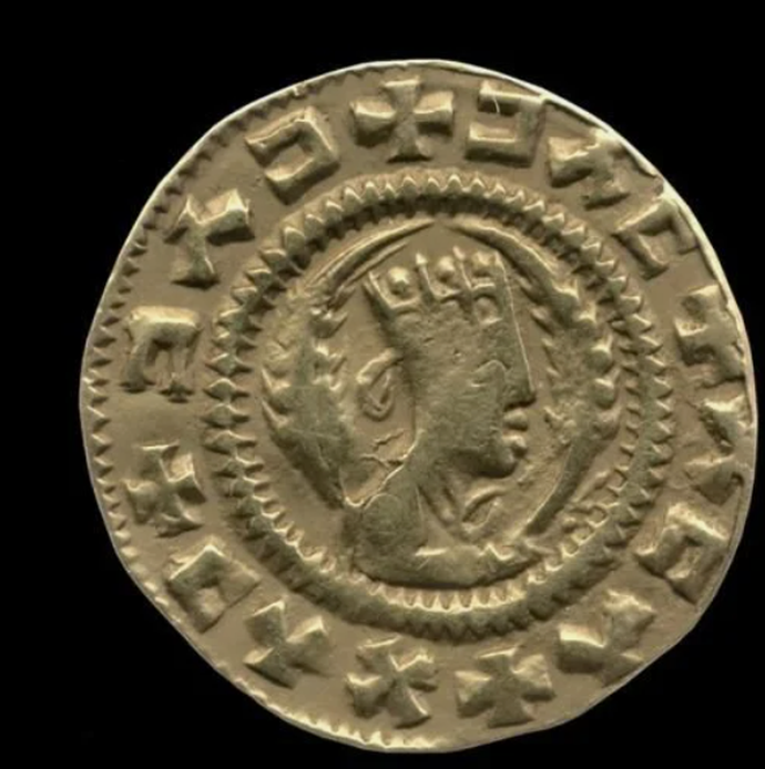 Ancient coin featuring a profile of a crowned figure, surrounded by inscriptions, on a dark background.