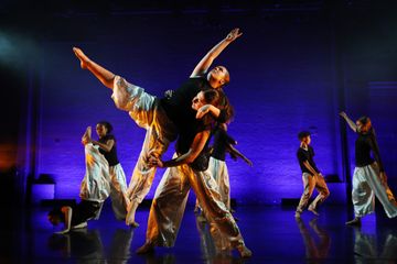 Dancers on stage performing in front of a deep blue backdrop