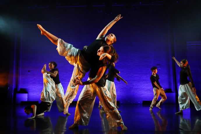 Dancers on stage performing in front of a deep blue backdrop