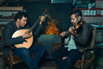 Two men playing musical instruments with fire behind them