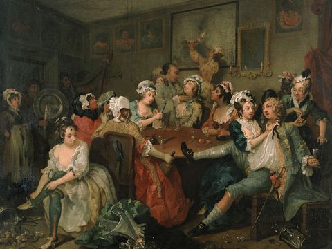 A lively, chaotic scene of people in 18th-century attire gathered around a table, drinking and socializing in a dimly lit room.