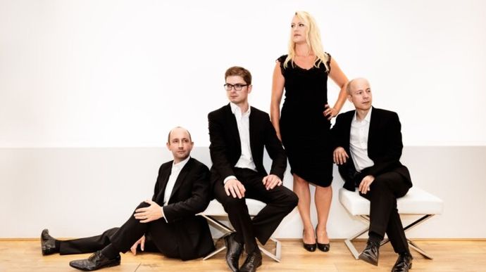 Four people in formal attire pose against a white background.