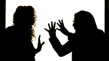 Silhouette of two people facing each other, gesturing with hands raised, against a bright background, suggesting a heated discussion.