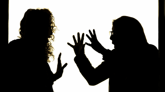 Silhouette of two people facing each other, gesturing with hands raised, against a bright background, suggesting a heated discussion.