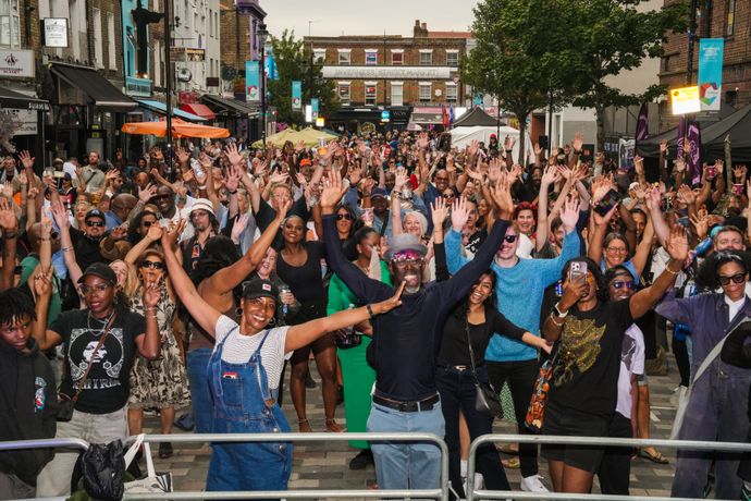 Group of people in street smile raising hands in the air