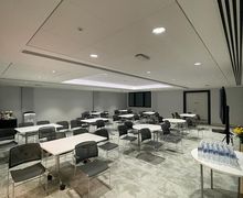 A large brightly lit room with white tables and black chairs in cabaret layout