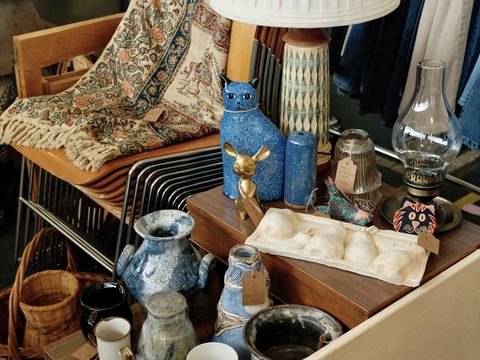 Collection of vintage homeware, ceramics, baskets, lamps and decorative items displayed on furniture.