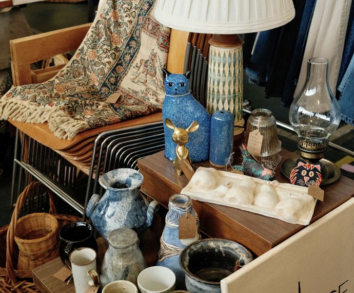 Collection of vintage homeware, ceramics, baskets, lamps and decorative items displayed on furniture.
