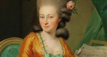 Historical-style portrait of a person wearing an ornate orange dress with green accents and lace trim, seated on a green chair. The hairstyle is voluminous and decorated with a pink rose. A sheet of music rests nearby on a surface draped with green fabric.