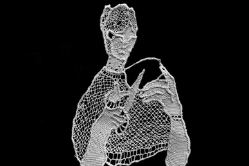 A delicate, lace-like human figure holds a pair of scissors against a stark black background.