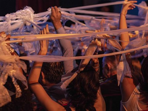 Audience members waving long, white ribbons above their heads in a lively atmosphere.