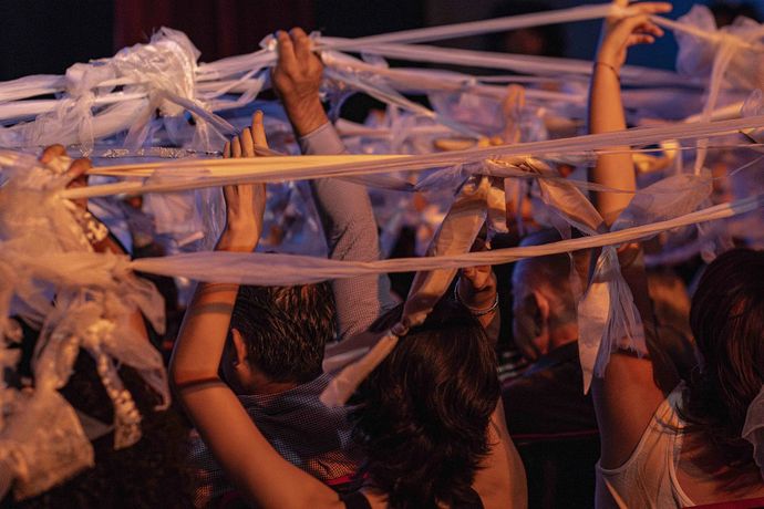 Audience members waving long, white ribbons above their heads in a lively atmosphere.