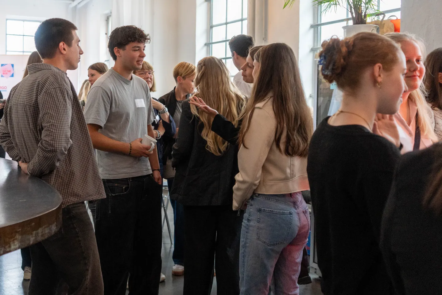 Gruppe junger Menschen in einem hellen Raum im Gespräch und beim Netzwerken