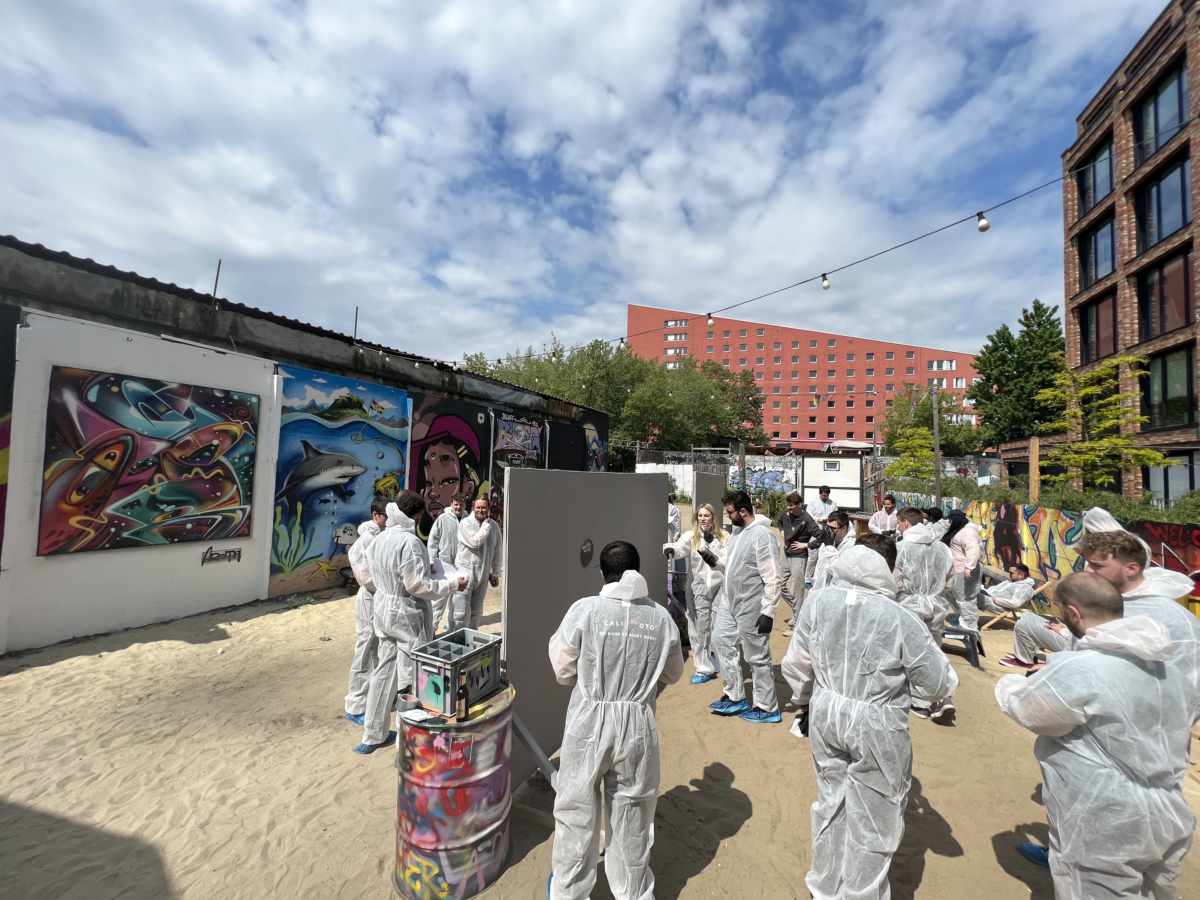 calimoto-Mitarbeitende tragen Schutzanzüge und bemalen Leinwände mit Graffiti.