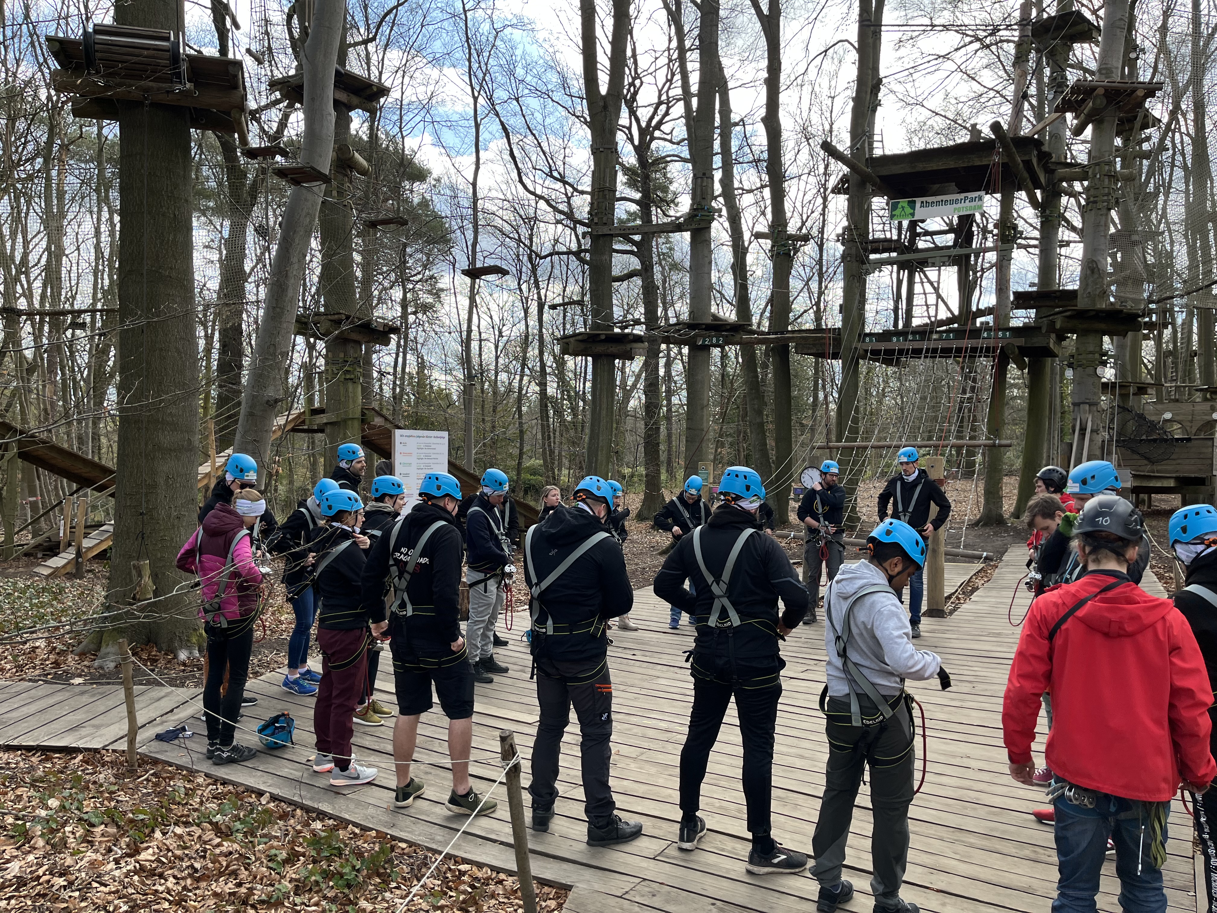 Teamevent im Kletterpark: Unsere Mitarbeiter stehen mit Helmen vor den Hindernissen.