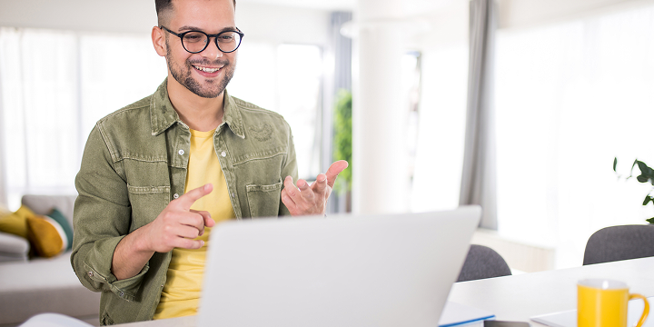 Eine Person schaut auf einen Laptop und spricht.
