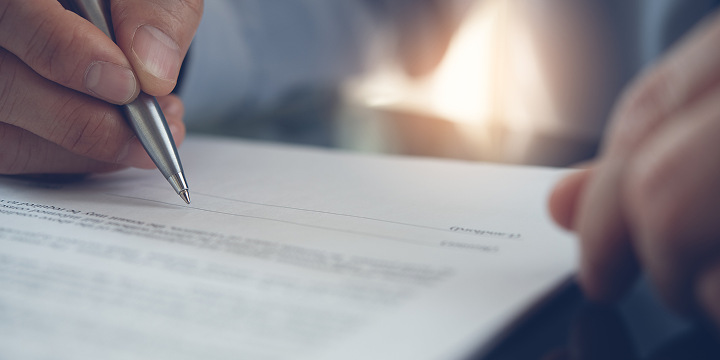 Eine Person unterschreibt mit einem Stift einen Vertrag,