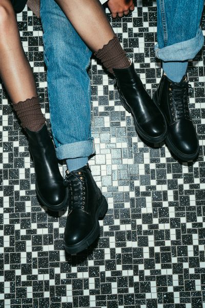 Two people showing their Sneaky Steve shoes on a tiled floor