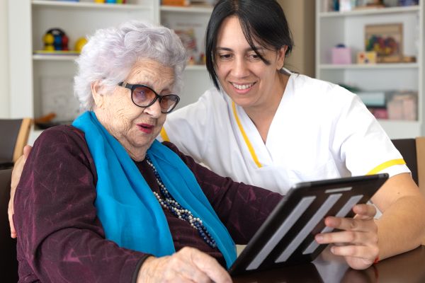Persona mayor y cuidadora usando una tablet