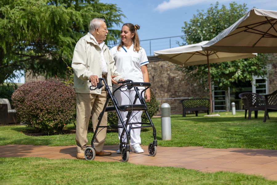 Persona mayor y cuidadora paseando