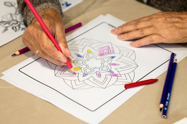 Manos de mayor dibujando en taller psicológico