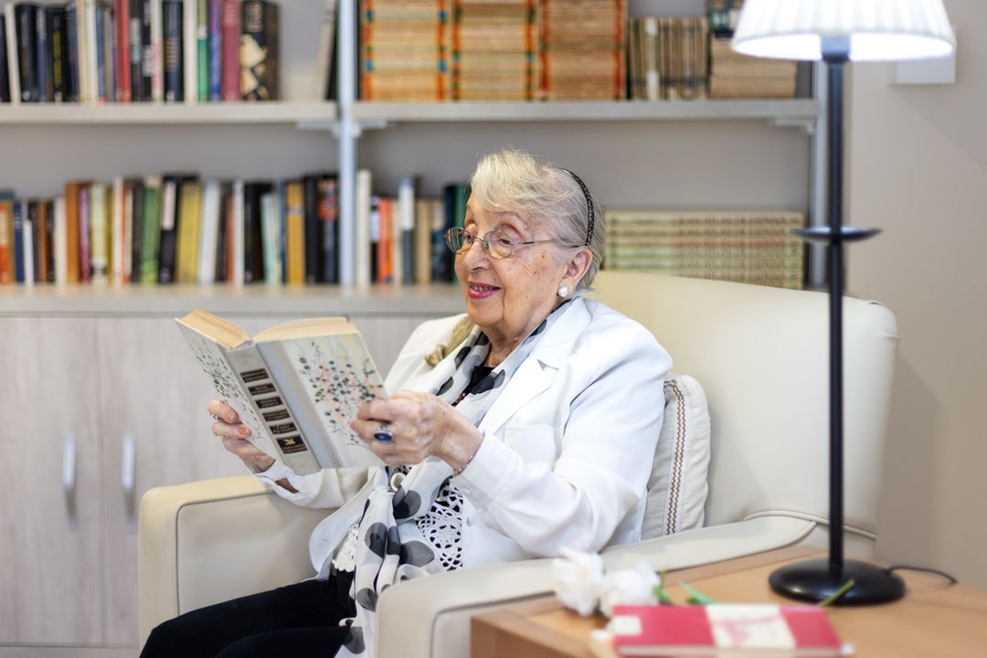Persona mayor leyendo un libro en la biblioteca