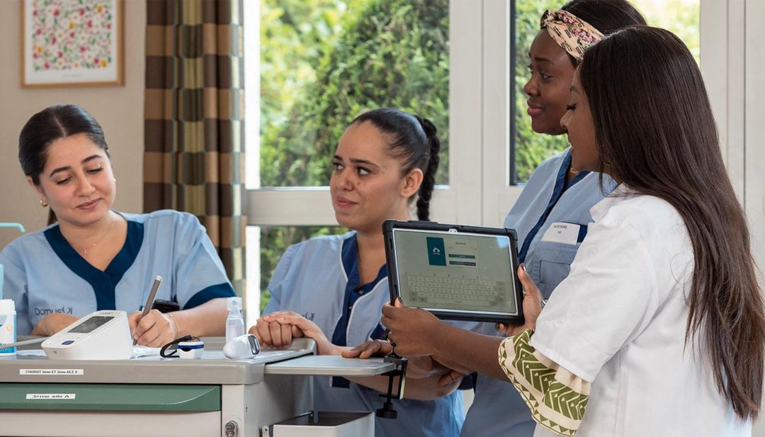 Une infirmière  prend des notes entouré de ses collègues