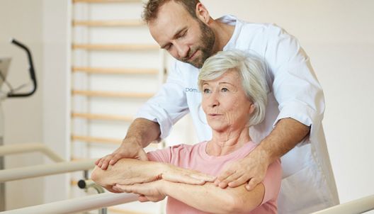 un kinésithérapeute avec une résidente en EHPAD