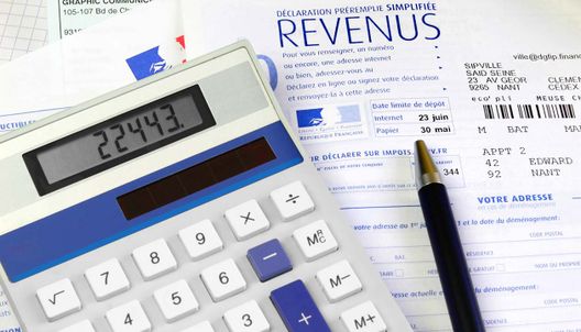 une feuille d'impôt, une calculatrice et un stylo