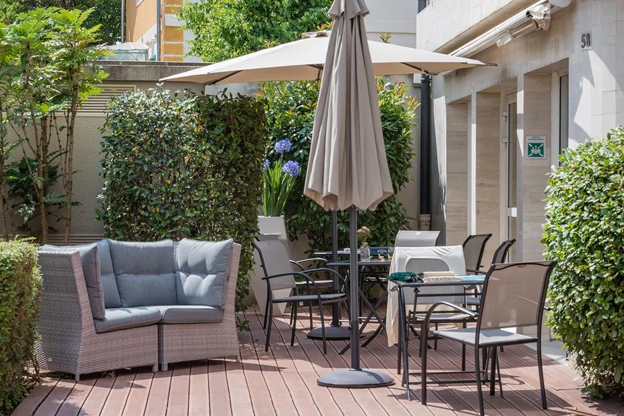 Terrasse extérieure avec canapé en osier, parasol, table à l'ehpad Esterel à Colombes
