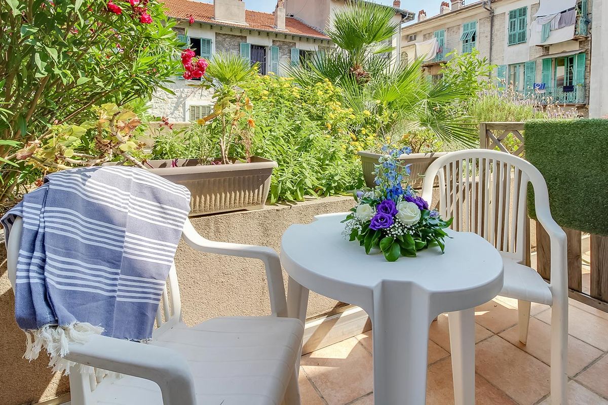 balcon fleuri avec table et chaises blanches, résidence bleu soleil à nice