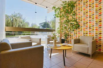 Veranda lumineuse avec sofa beige et décoration en maison de retraite à Marseille, Saint-Anne