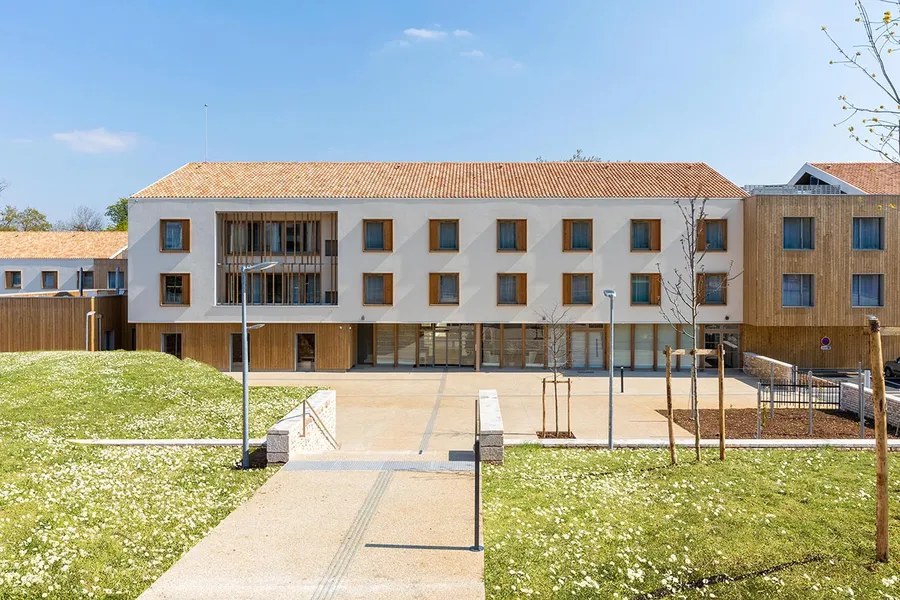 Facade maison retraite naturel blanc et bois avec jardin pelouse et grande cour