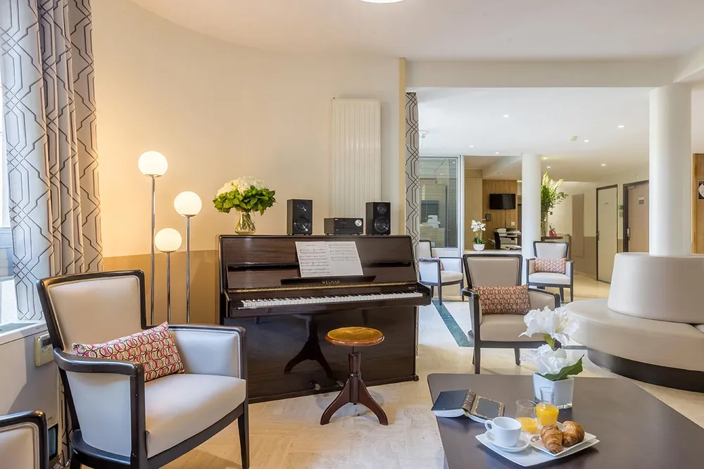 Salon de détente avec chaises confortables et piano dans une maison de retraite à Colombes