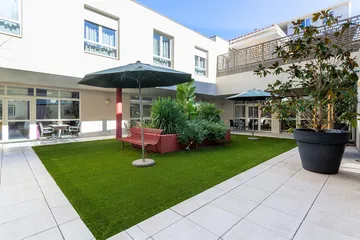 Cour intérieur ehpad résidence longchamp à marseille avec pelouse et parasol