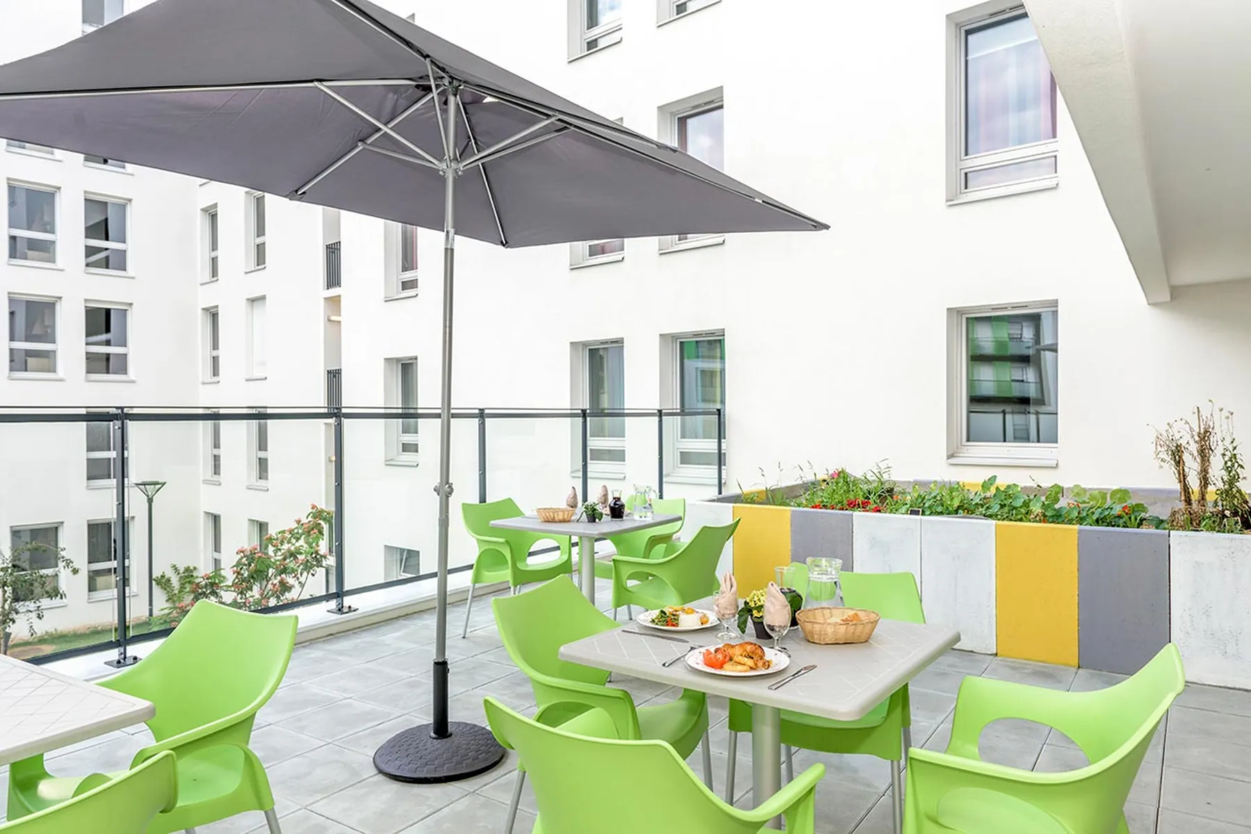Balcon cour intérieure Résidence Les Intemporelles Aubervilliers vue facade blanc chaise verte parasol