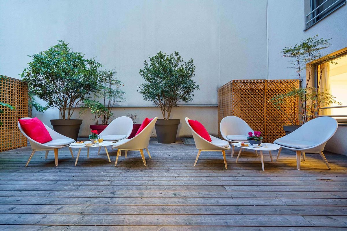 Cours intérieure chaleureux décorée avec fauteils et végétation Résidence Ornano à Paris