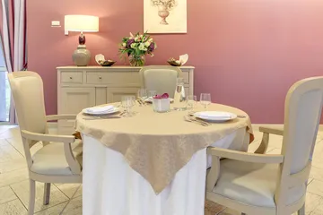 Table ronde dressée chaises beige mur framboise girly ehpad à Esches, Résidence Les Jardins Médicis