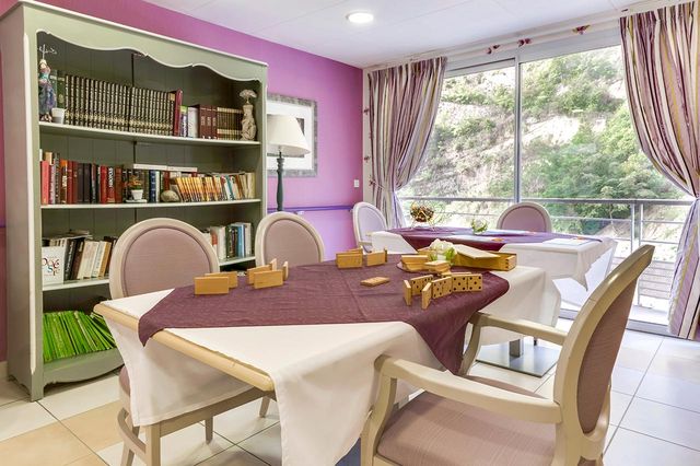 Salon lumineux avec grandes tables, chaises beige et jeu de domino à La Palmeraie à Nice