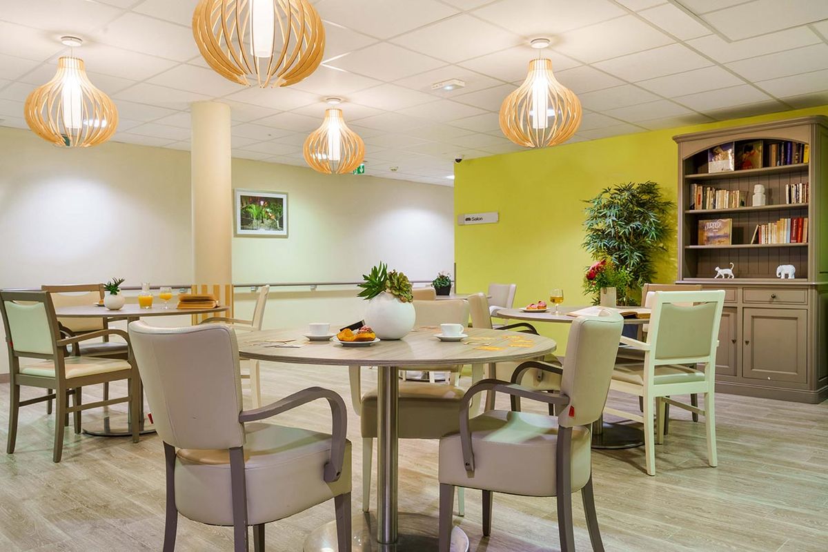 Salon vert pistache décorée avec livres et tables rondes Résidence Ornano à Paris