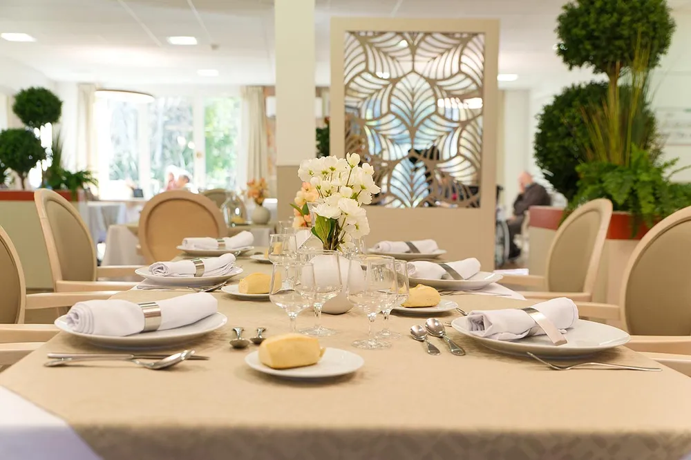 Zoom table blanche mariage avec orchidée et pain en ehpad à Marseille, Résidence Médicis