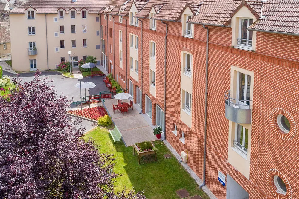 Immeuble rouge brique avec entrée et jardin roseraie, ehpad à Trie Château, Les Jardins de la Tour