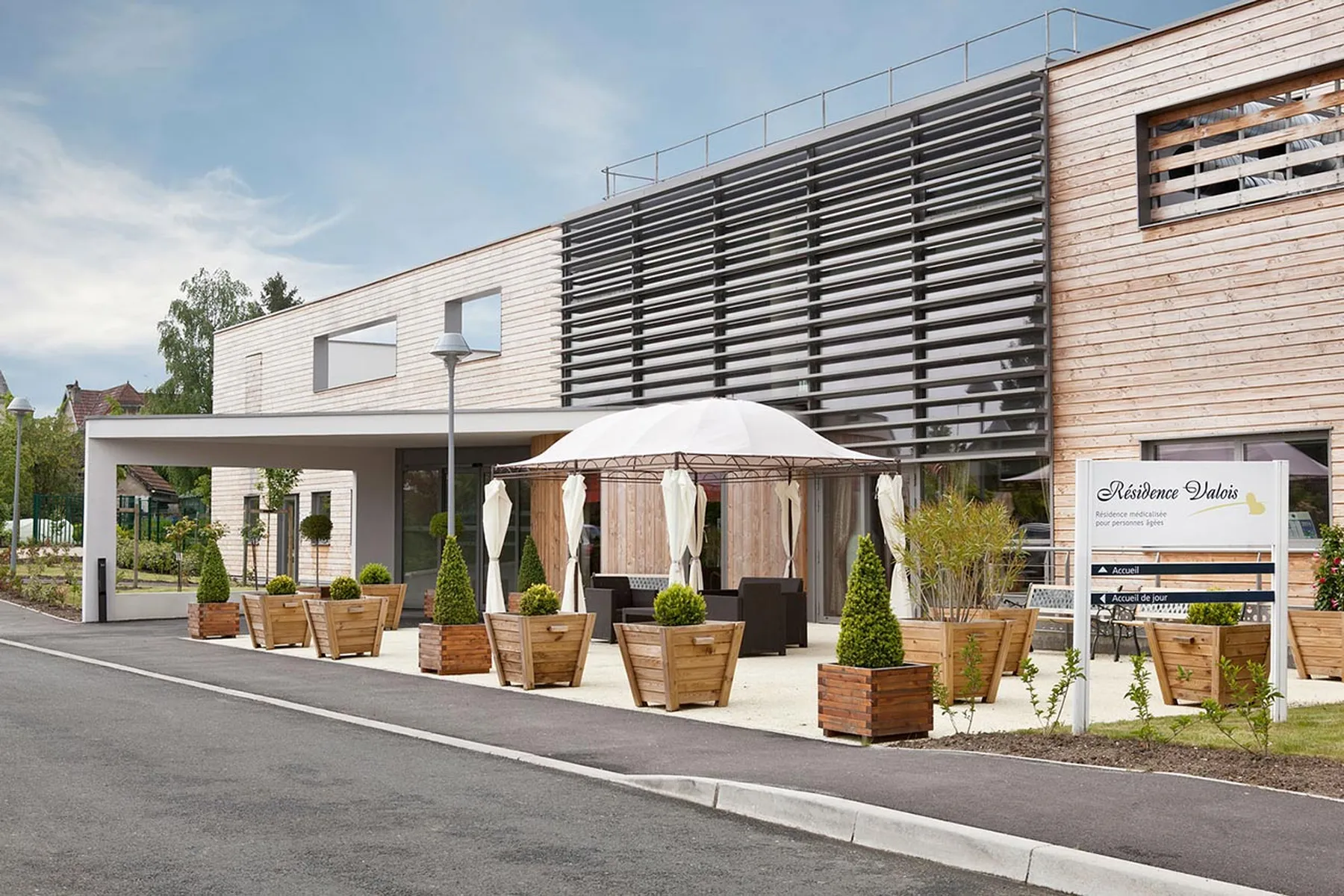 Résidence médicalisée orléans valois cubique facade bois sur route plante parasol blanc