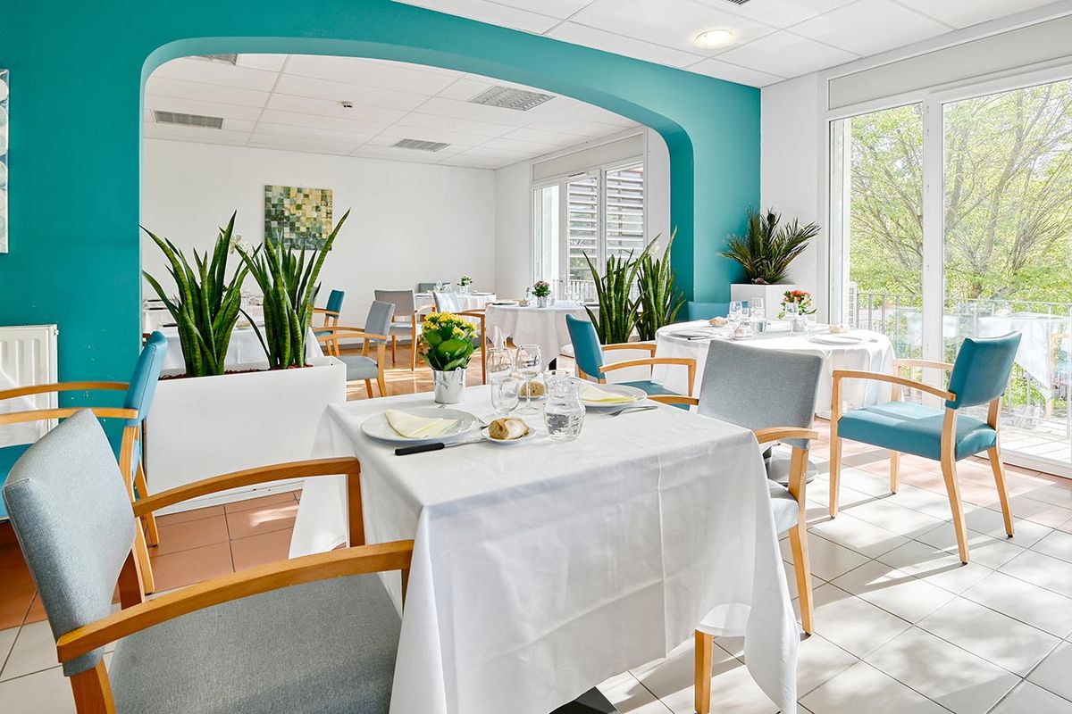 Salle de restauration Maison de retraite Lubéron à Sainte-Tulle avec arche intérieur bleu et belle luminosité, plantes et décorations
