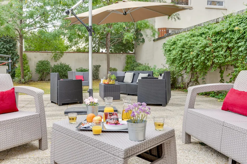 Espace extérieur convivial avec fauteuils et parasol à l’EHPAD Rabelais à Asnières