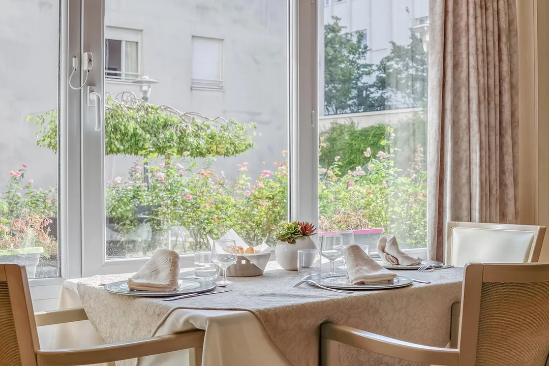 Table à manger près d'une fenêtre donnant sur un jardin maison de retraite à Asnières
