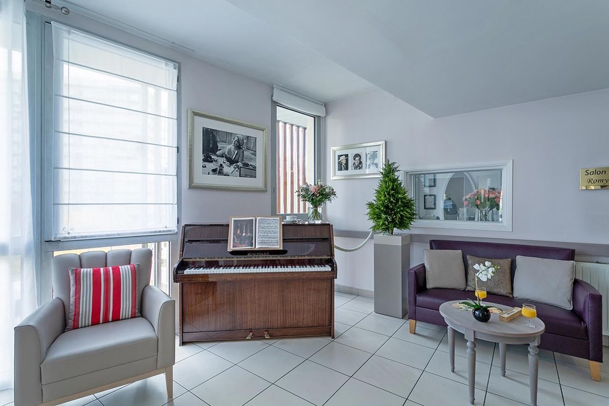 Salon avec piano marron et canapé gris, maison de retraite Médicis à Asnières